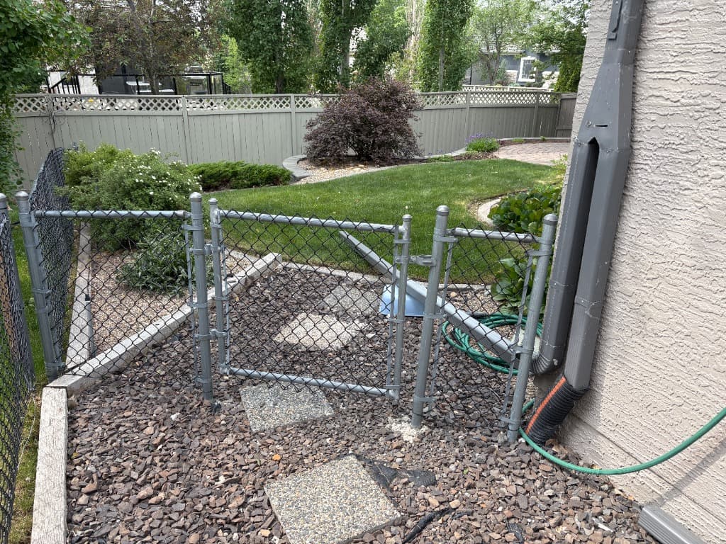 Chainlink gate showing old rock and square steppers