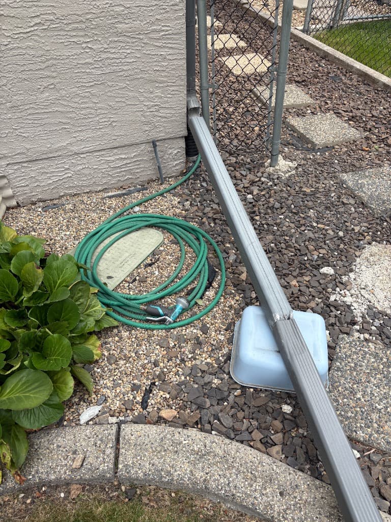 Downspout draining onto old mixed rock and steppers